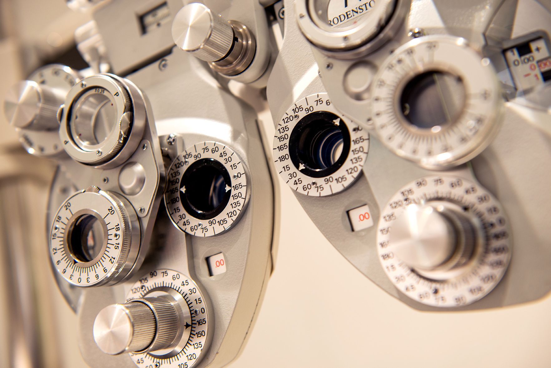 Close-up of a gray ophthalmic phoropter with multiple dials and lenses used for eye exams.