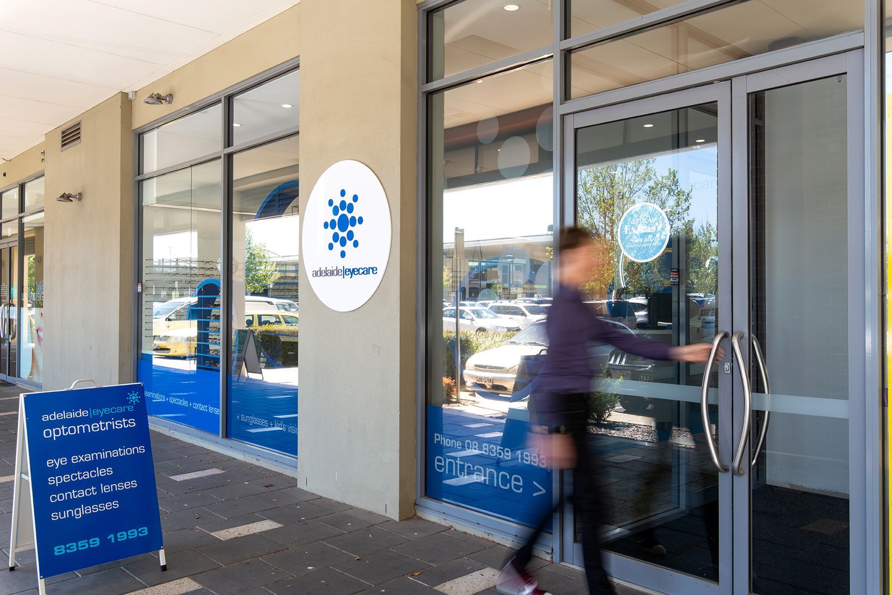 Exterior of a business with a sign. A person opens the door.